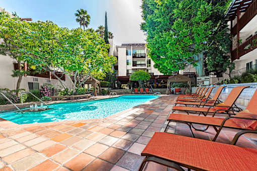 A pool surrounded by trees and chairs.
