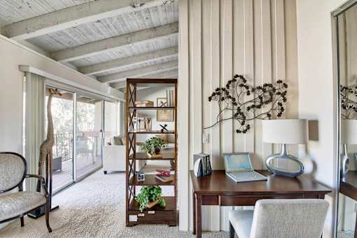 a home office with a wooden desk and a laptop at Mediterranean Village Costa Mesa, Costa Mesa