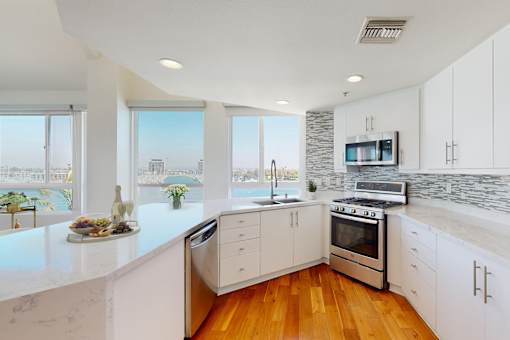 A modern kitchen with white cabinets and a marble countertop at Esprit Marina del Rey, 90292