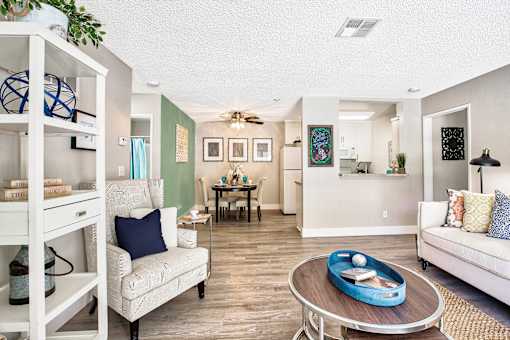 A living room with a white couch, a coffee table, and a dining table.