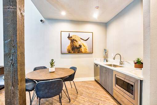A kitchen with a table and chairs and a painting of a bison on the wall.