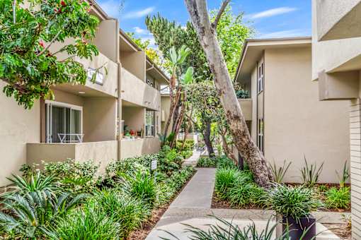 A row of beige apartment buildings with green plants in front at West Park Village, Los Angeles, CA