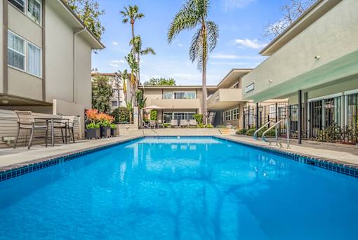 A swimming pool in a residential area with houses and palm trees.