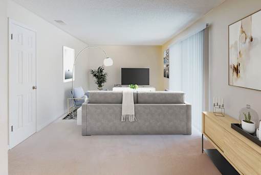 A person is sitting on a chair in a room with a grey couch and a television.