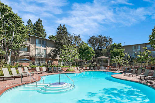 A large swimming pool surrounded by lounge chairs and trees at The Meadows Apartments, Culver City , CA 90230
