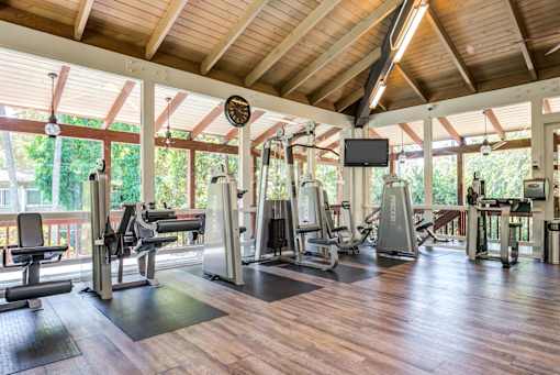 A gym with a variety of equipment including treadmills, weights, and a television at Rancho Los Feliz, Los Angeles, California