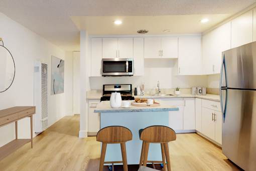 A kitchen with a blue island and stainless steel appliances.