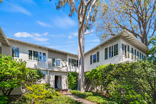 A white two-story house with a tree in front.