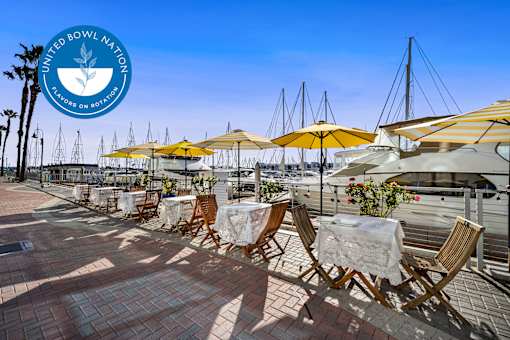 A sunny day at the outdoor seating area of a restaurant with yellow umbrellas at Esprit Marina del Rey, 90292