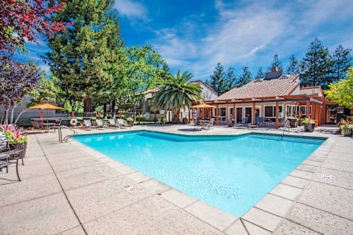 A large swimming pool surrounded by trees and a house in the background at Valley Plaza Villages, California, 94566