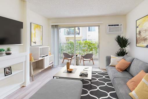 A living room with a grey couch and a black and white rug at Village Pointe Apartments, Northridge, California
