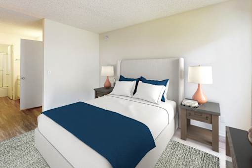 A bedroom with a large bed and a nightstand with a lamp at Village Pointe Apartments, Northridge, California