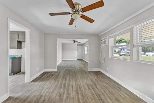 A room with a ceiling fan and wooden flooring.