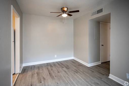 A room with a ceiling fan and light fixture, and a wooden floor.