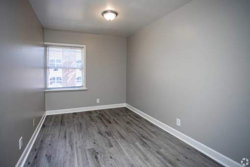 A room with a window and wooden flooring.