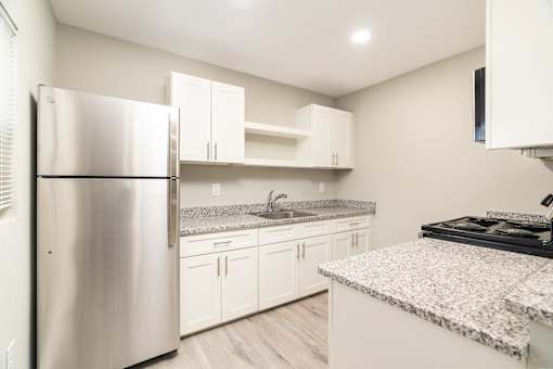 A modern kitchen with a granite countertop and stainless steel appliances.