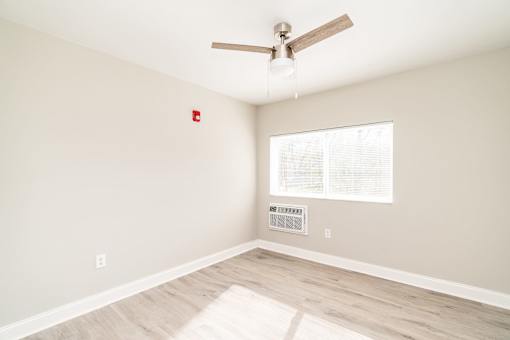 A room with a ceiling fan and a window with blinds.