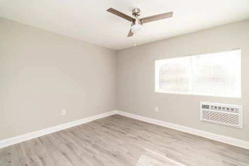 A room with a ceiling fan and a window with blinds.