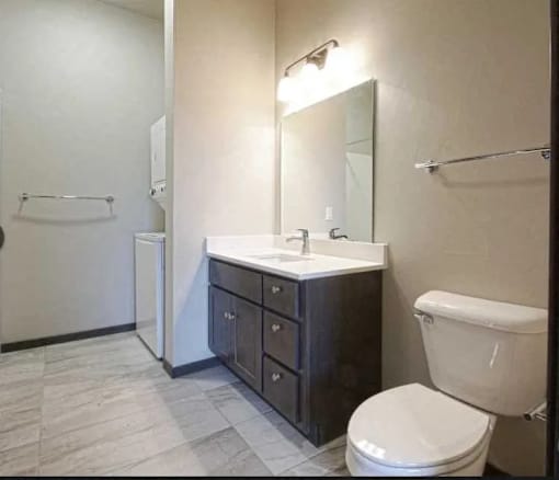 A bathroom with a white toilet, a sink with a mirror and a towel rack.