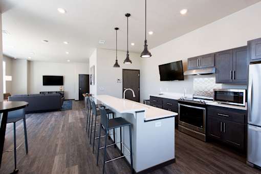 A modern kitchen with dark wood floors and stainless steel appliances.
