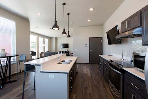 A modern kitchen with dark wood floors and a white island.