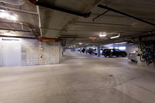 A parking garage with a few cars and bicycles.