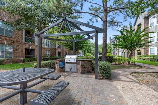 Grilling station with picnic table under a pergola at Asheville at Spring Branch apartments in Houston, TX