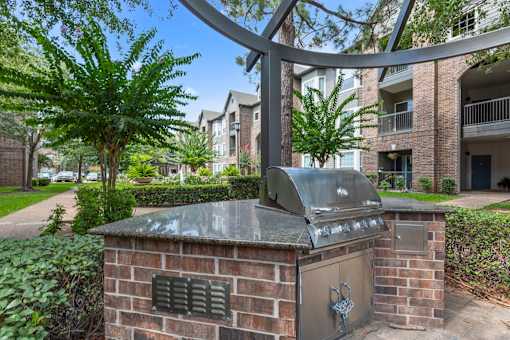 Grilling station with steel BBQ grill under a pergola at Asheville at Spring Branch apartments in Houston, TX