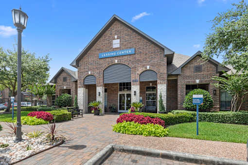Leasing office front surrounded by a well-manicured garden at Asheville at Spring Branch apartments in Houston, TX