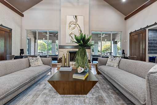 Leasing office lounging area with grey couches and large windows at Asheville at Spring Branch apartments in Houston, TX