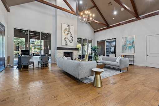 Leasing office interior with grey sofas and wooden floors at Asheville at Spring Branch apartments in Houston, TX