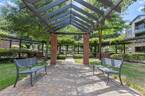 Beautiful outdoor spaces with benches under a pergola at Asheville at Spring Branch apartments in Houston, TX