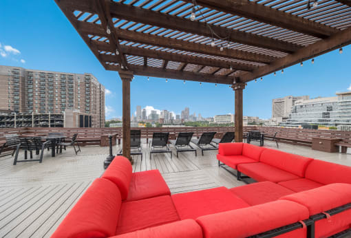 a rooftop deck with red couches and a pergola