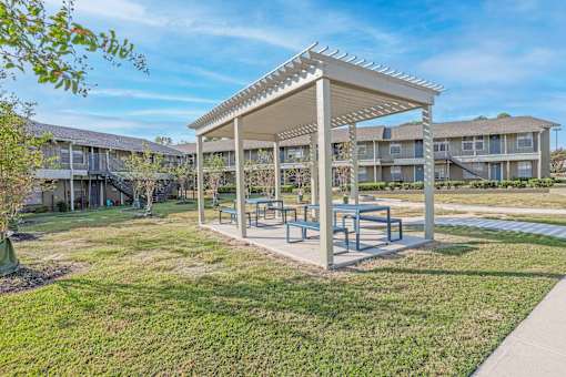 A covered picnic and barbeque area in front of apartment buildings  at The Creole Apartments in Shreveport, LA
