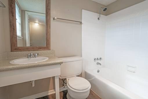 A bathroom with a toilet, sink, and white bathtub  at The Creole Apartments in Shreveport, LA