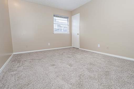 A bedroom with a carpeted floor and a closet  at The Creole Apartments in Shreveport, LA