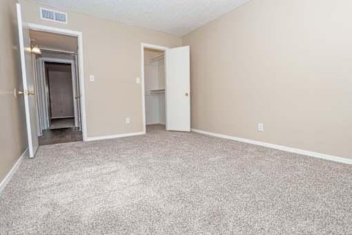 A bedroom with a carpeted floor and beige walls  at The Creole Apartments in Shreveport, LA