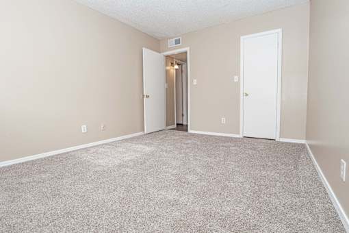 A bedroom with carpeted floor and a closet  at The Creole Apartments in Shreveport, LA