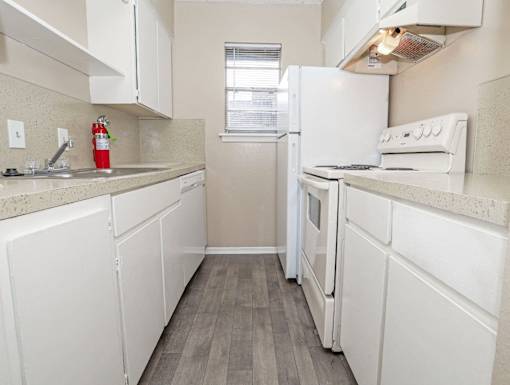 A kitchen with white appliances and cabinets  at The Creole Apartments in Shreveport, LA