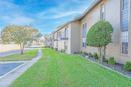 Apartment buildings with second-floor balconies and green grass outside   at The Creole Apartments in Shreveport, LA