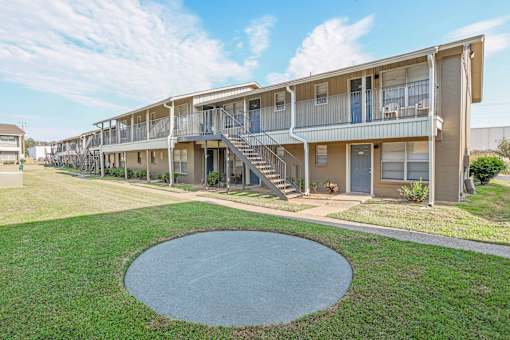 A concrete circle is in the middle of a grassy area in front of apartment buildings  at The Creole Apartments in Shreveport, LA