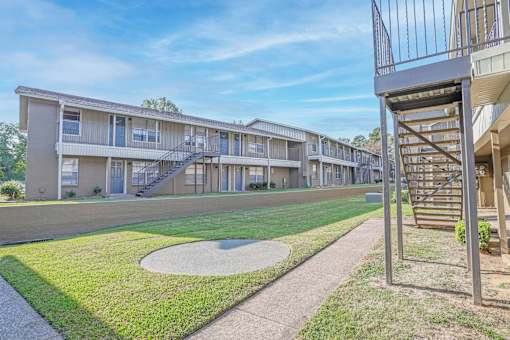 A view of apartment buildings with a metal staircase on the right at The Creole Apartments in Shreveport, LA