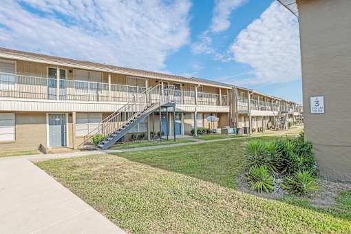 Apartment complex with a blue sky and clouds in the background at The Creole Apartments in Shreveport, LA