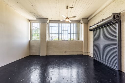 an empty room with a garage door and a ceiling fan