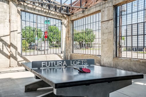 a ping pong table sits in front of a window with a street sign that reads fut