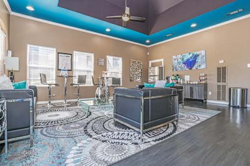A modern clubhouse with a ceiling fan and a patterned rug at The Drake in Bossier City, LA