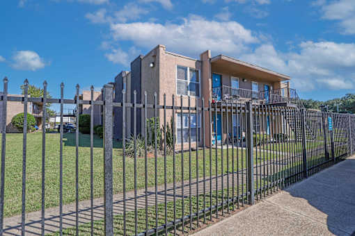 A modern apartment building with a black fence in front at The Drake in Bossier City, LA