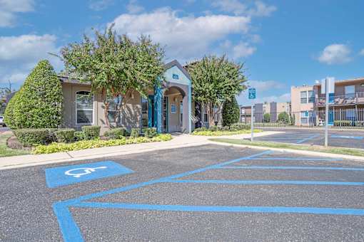 The leasing office parking lot with a disabled parking sign painted on the pavement at The Drake in Bossier City, LA