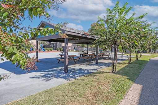 A paved pavilion with picnic tables is surrounded by trees at The Drake in Bossier City, LA