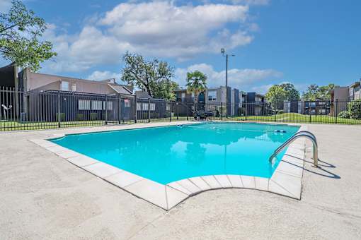 A rectangular pool with a white border and a black fence around it at The Drake in Bossier City, LA